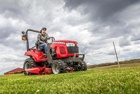 Massey Ferguson GC1700 Series sub-compact tractor mowing large lawn with mid-mount mower deck under cloudy skies