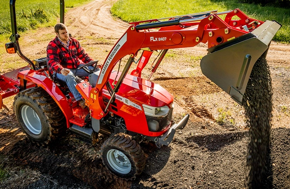 Massey Ferguson 1800 E Series compact tractor using FLX 2407 front loader to spread gravel on a dirt path