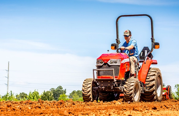 Massey Ferguson 1800 E Series compact tractor tilling soil in a freshly plowed field