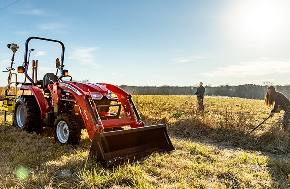 Massey Ferguson 1800 E Series compact tractor with loader parked in field as users clear brush