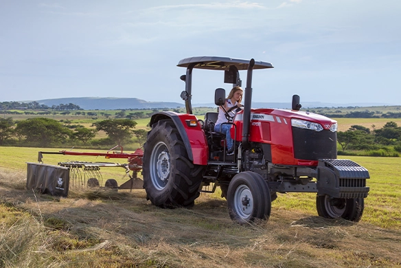 Massey Ferguson 4700 Series tractor with MF RK451 rotary rake driven by female operator in open field
