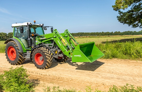 Fendt 200 Vario mid-range tractor with front loader and bucket driving on rural dirt road