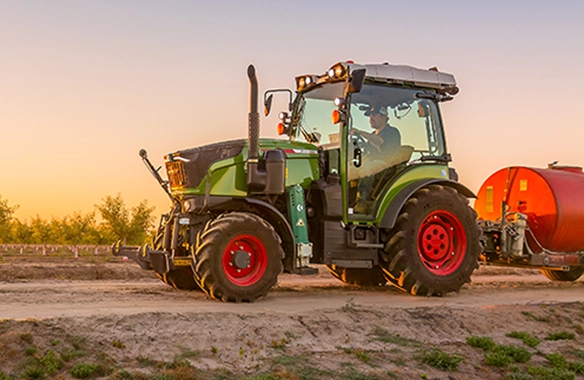 Fendt 200 Vario tractor pulling liquid applicator at sunrise in orchard or vineyard setting