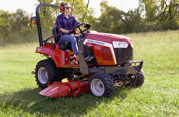 A woman operates a Massey Ferguson 1GC series tractor while mowing a field, highlighting ease of use and operator comfort.