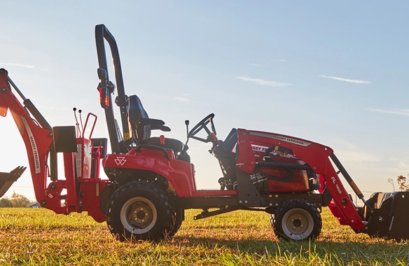 Side profile of Massey Ferguson 1GC Series sub-compact tractor with backhoe and loader at sunrise