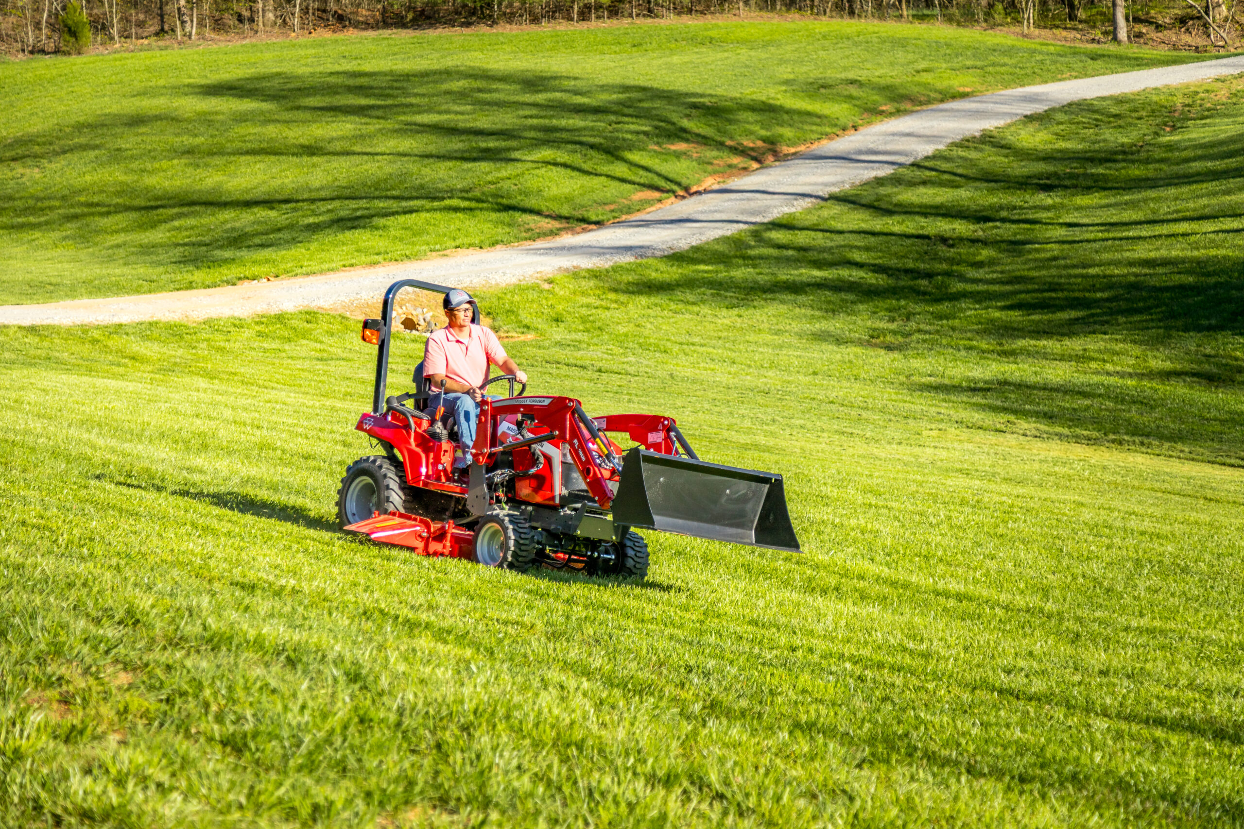 Massey Ferguson 1GC Series sub-compact tractor mowing sloped yard with front loader and mid-mount mower