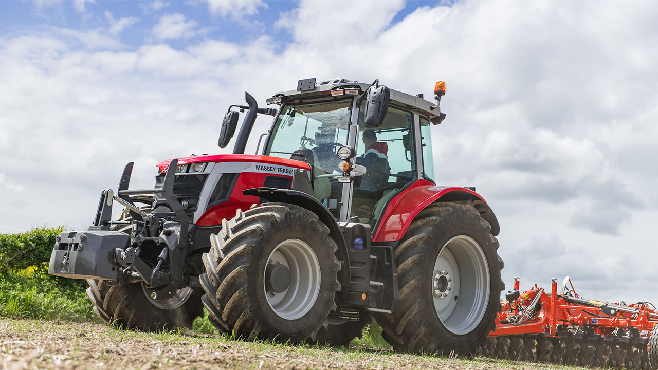 Massey Ferguson 6S Series high-horsepower tractor pulling tillage equipment under a cloudy sky.